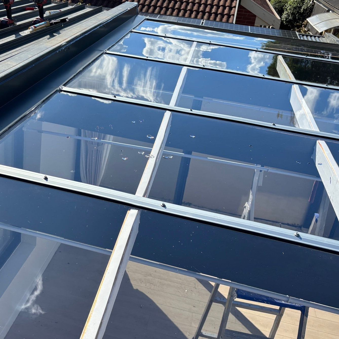 Glass-like polycarbonate roof with metal joiners on a pergola